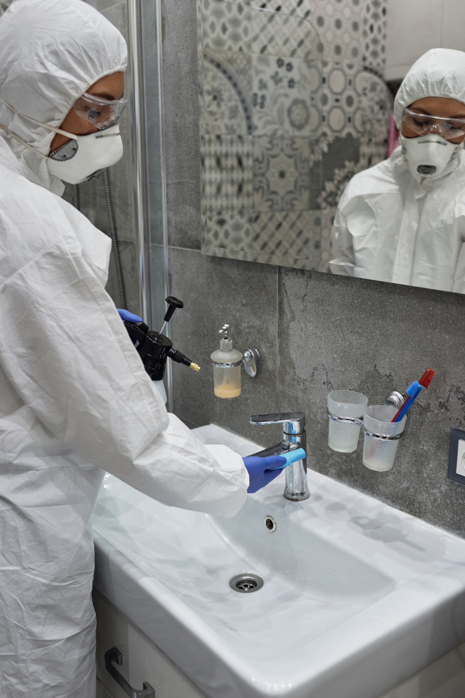 Koruyucu ekipmanlı görevli, konut banyosunda lavabo ve gider çevresine uygulama yaparken